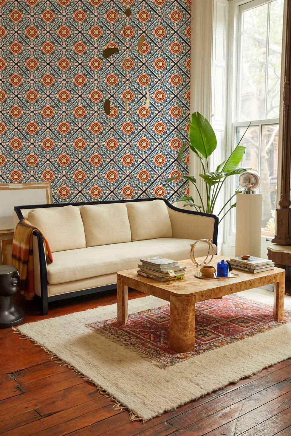 Moroccan Geometric Pattern Wallpaper in blue and orange complements beige sofa and wooden flooring.