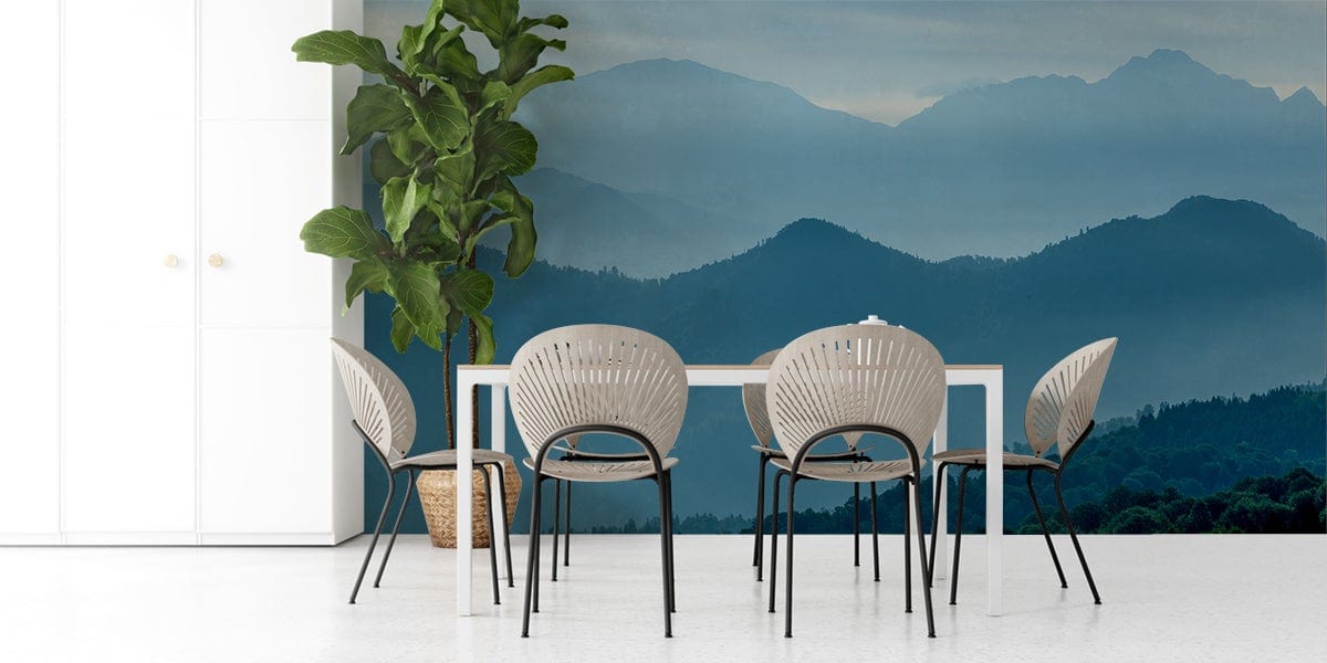 Tranquil blue mountain mural wallpaper in dining room with white table, modern chairs, and green plant.