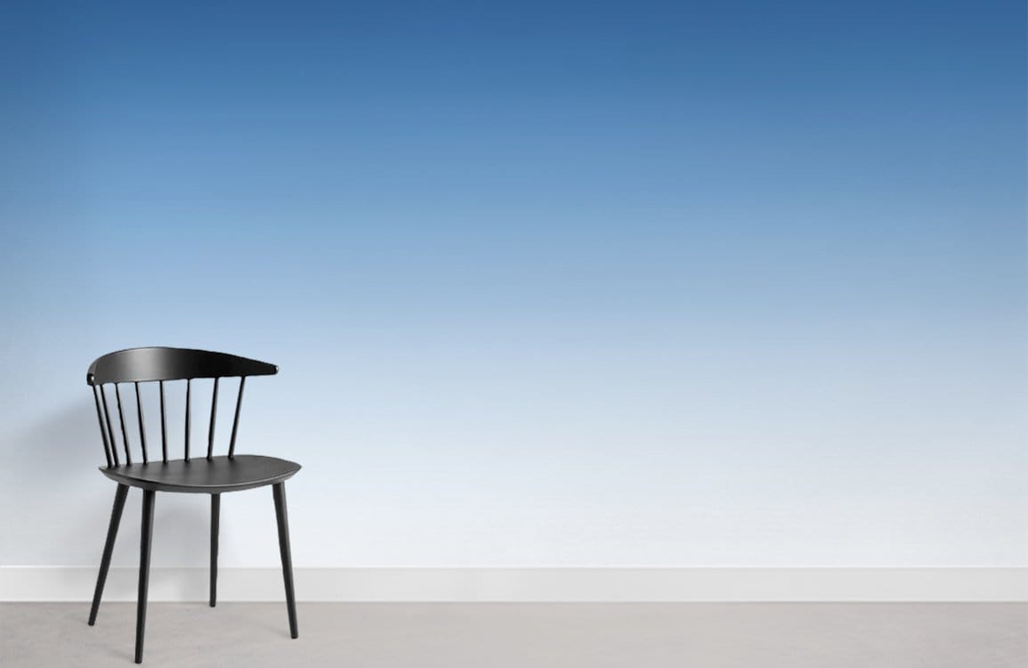 Serene Blue Gradient Ombre Wallpaper with black chair, minimalist white wall, grey flooring, modern style.