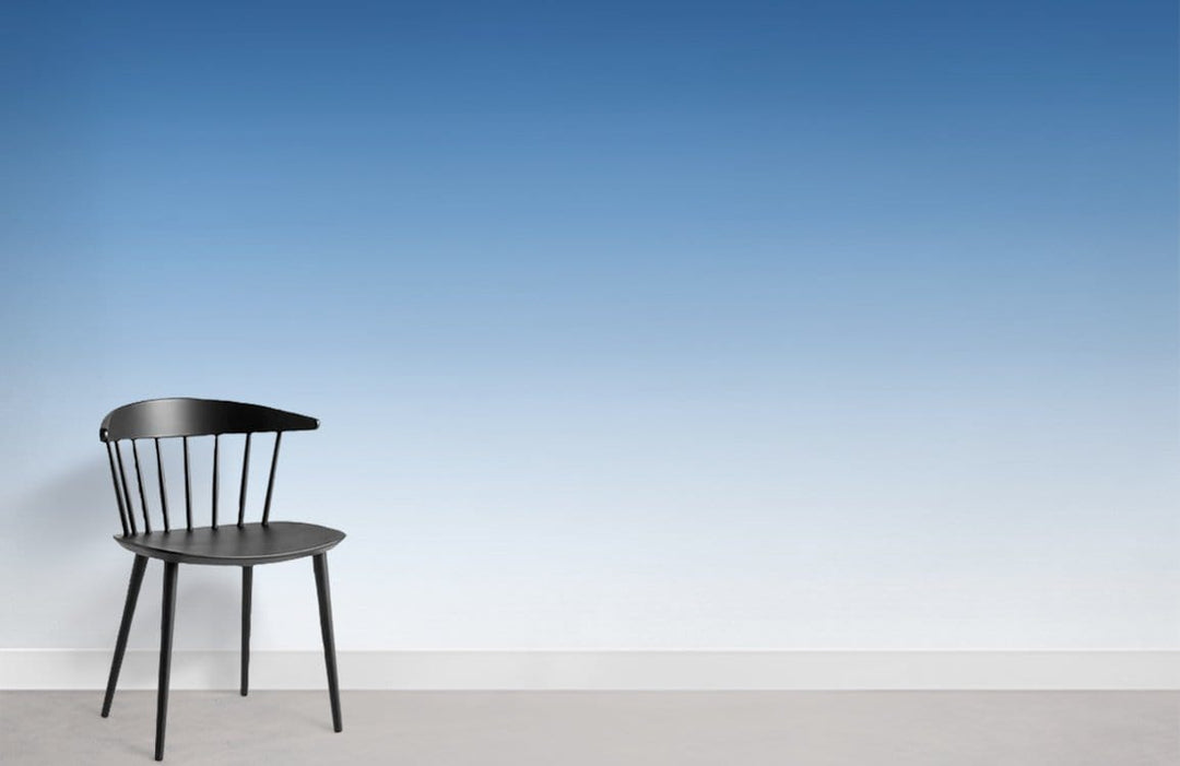 Serene Blue Gradient Ombre Wallpaper with black chair, minimalist white wall, grey flooring, modern style.