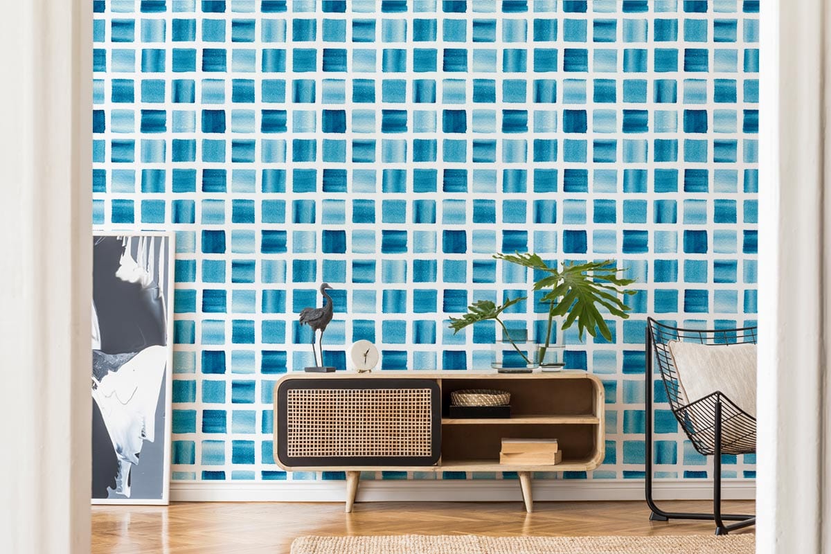 Modern blue geometric grid wallpaper in stylish interior with wooden sideboard, wicker chair, hardwood flooring.