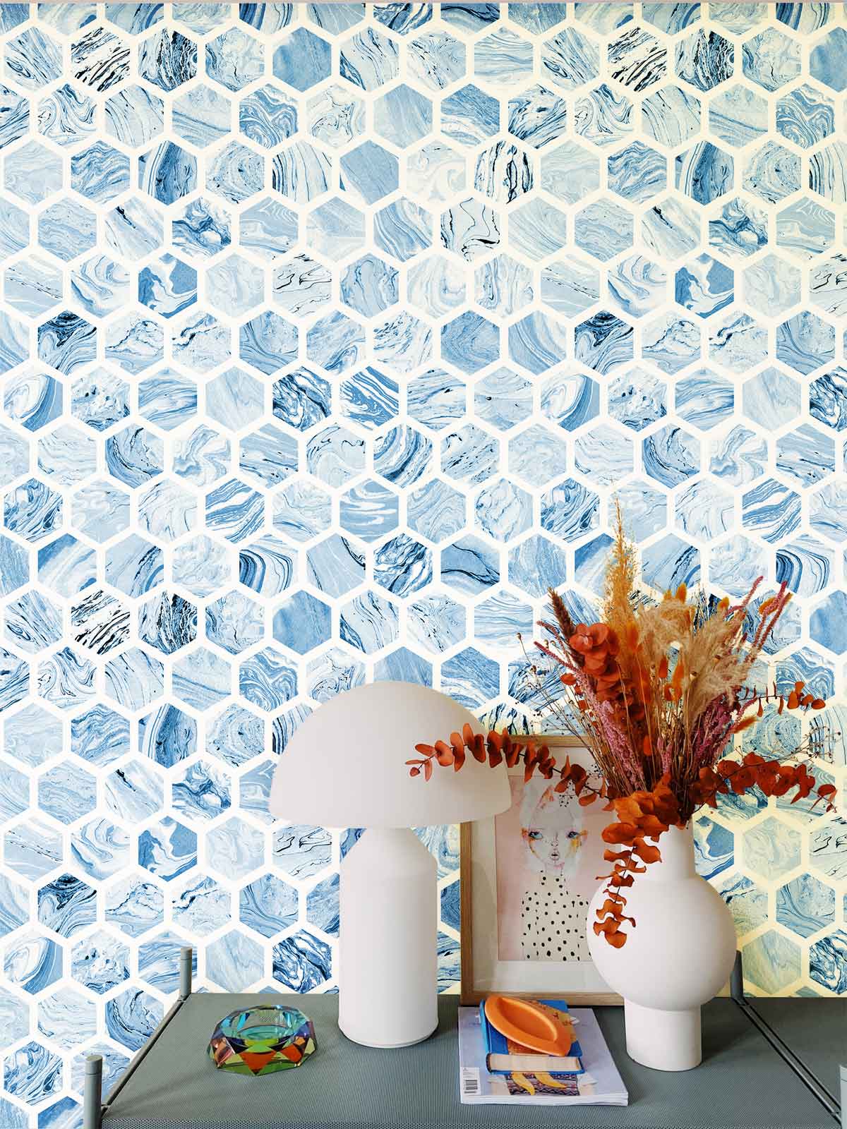 Elegant blue hexagonal patterned wallpaper in modern interior with grey table, white lamp, decorative items.