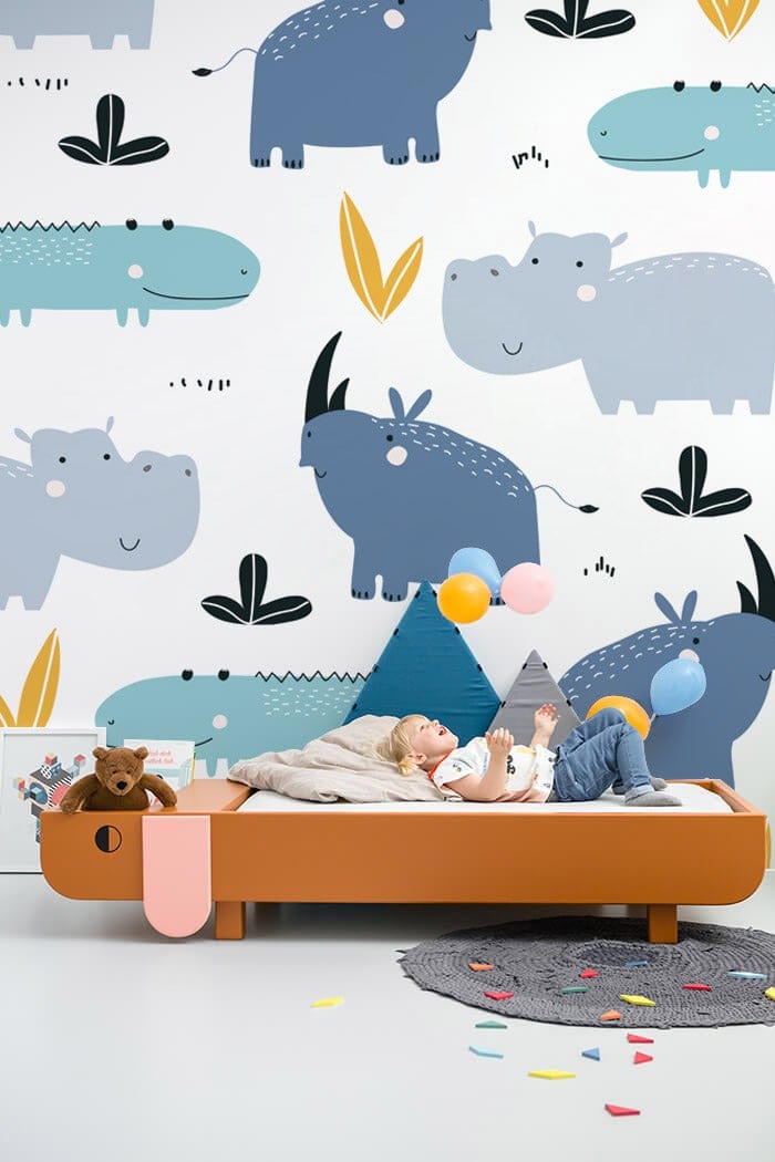 Playful Safari Animals wallpaper, pastel blue-yellow design, children's bedroom, featuring orange children's bed.