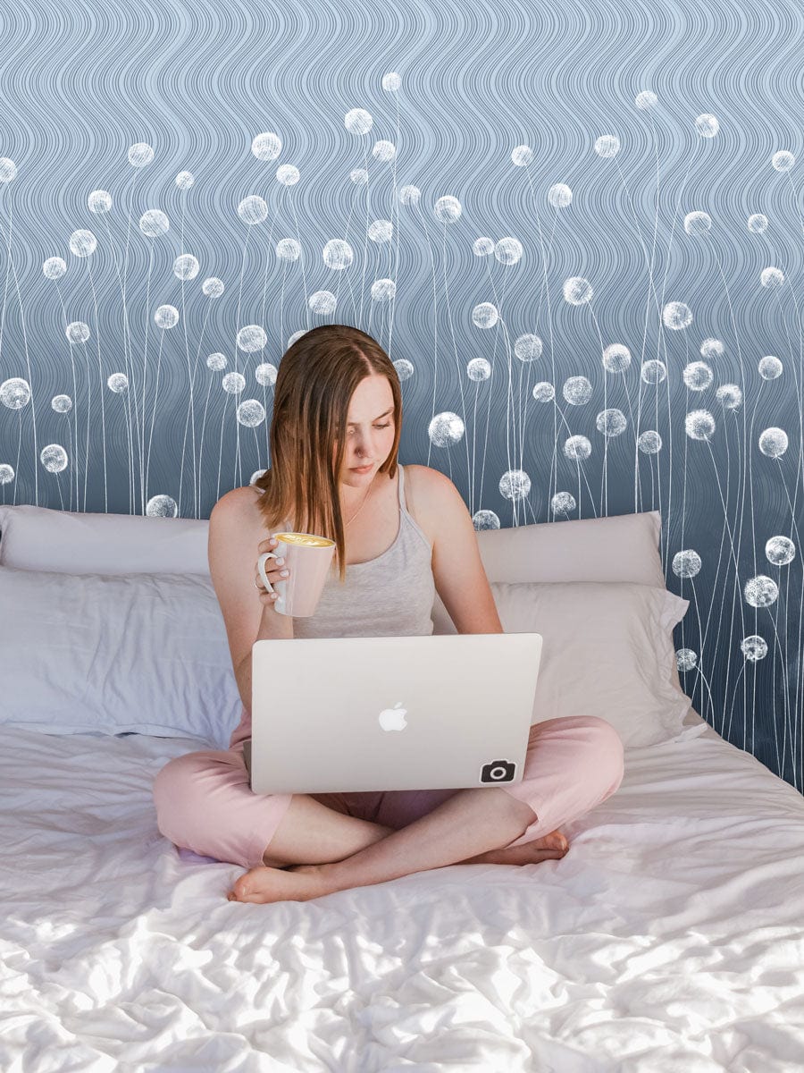 Woman on bed with laptop, backed by Elegant Grey Wavy Floral Mural Wallpaper, modern decor design.