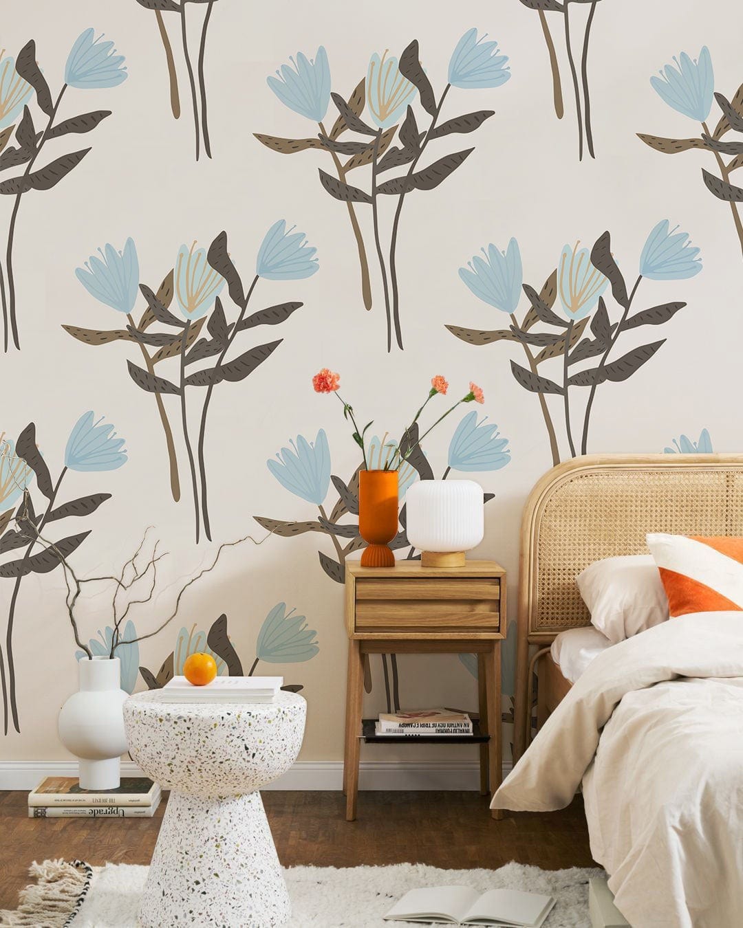 Blue floral wallpaper in bedroom with rattan headboard, terrazzo table, wooden flooring, and modern decor.