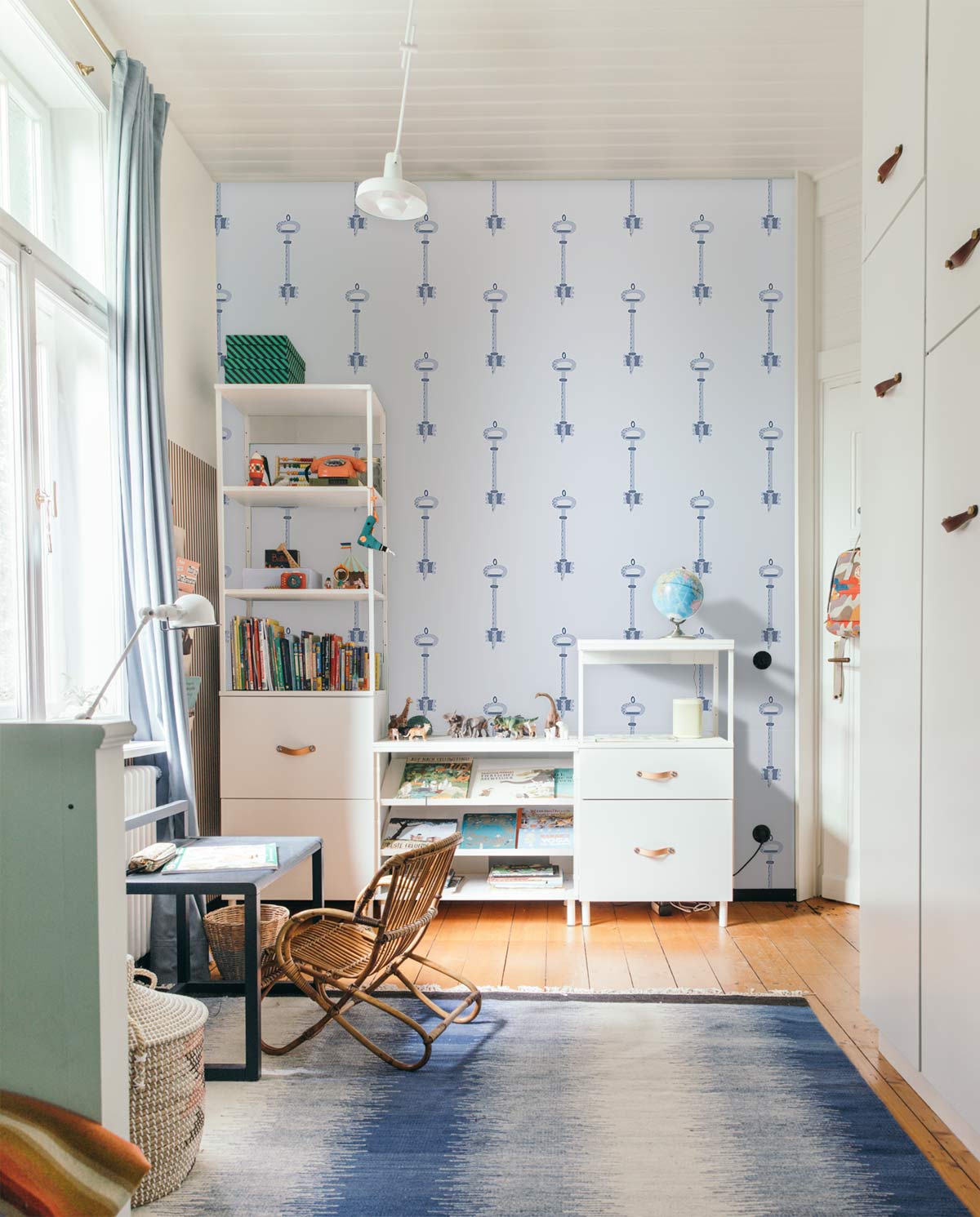 Vintage blue key patterned wallpaper in study room with white shelves, wooden flooring, and elegant decor.