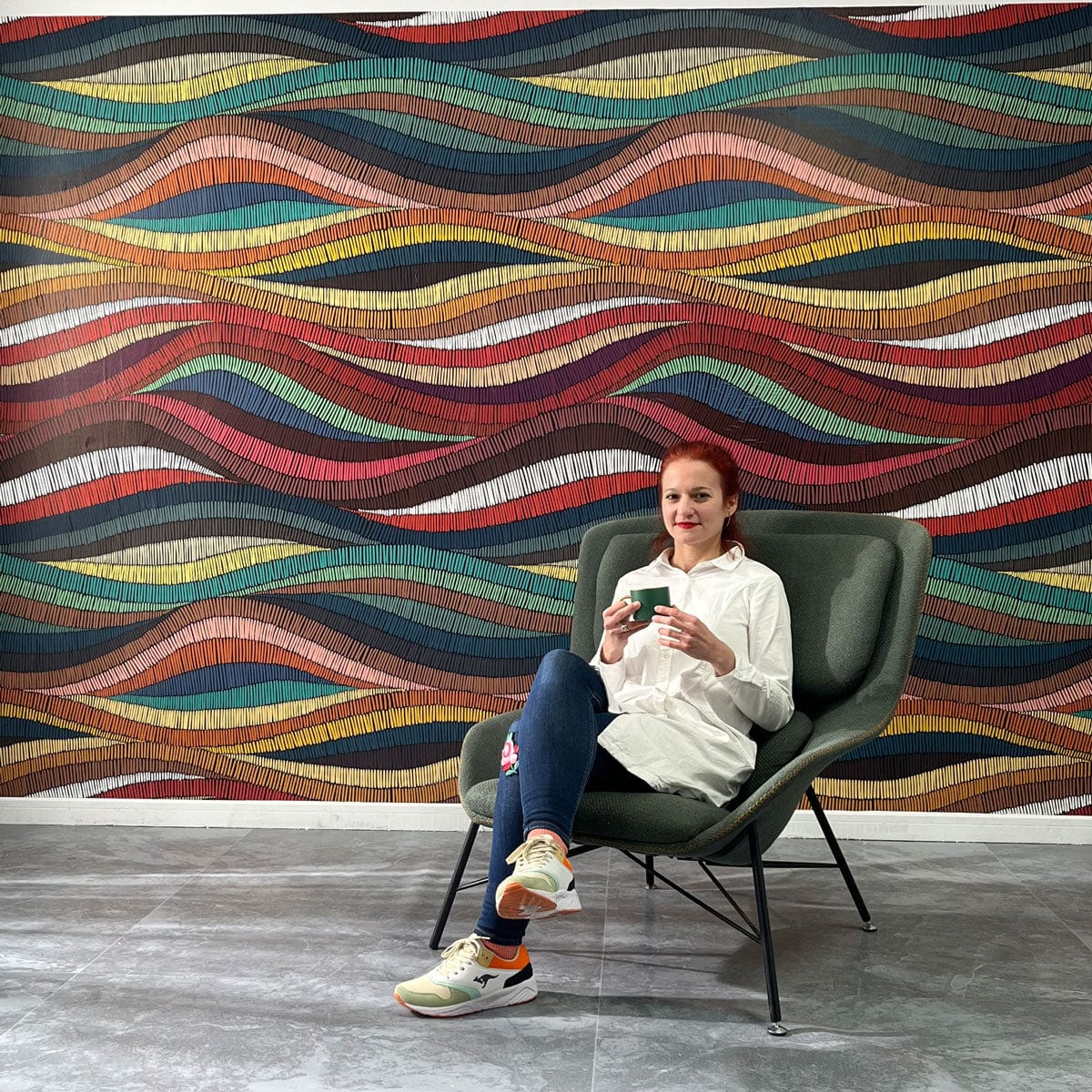 Colourful Geometric Wave Pattern Wallpaper in modern room with grey flooring and green armchair.
