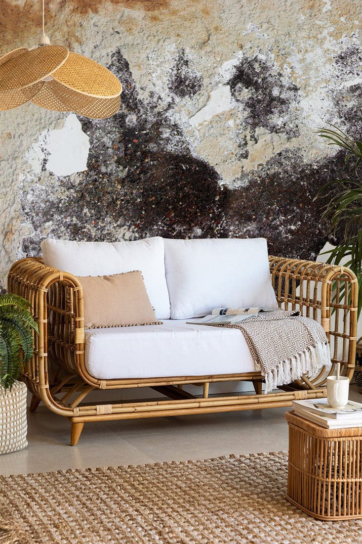Vintage rustic mural wallpaper with earthy pattern, wicker sofa, rattan table, beige rug, airy room.