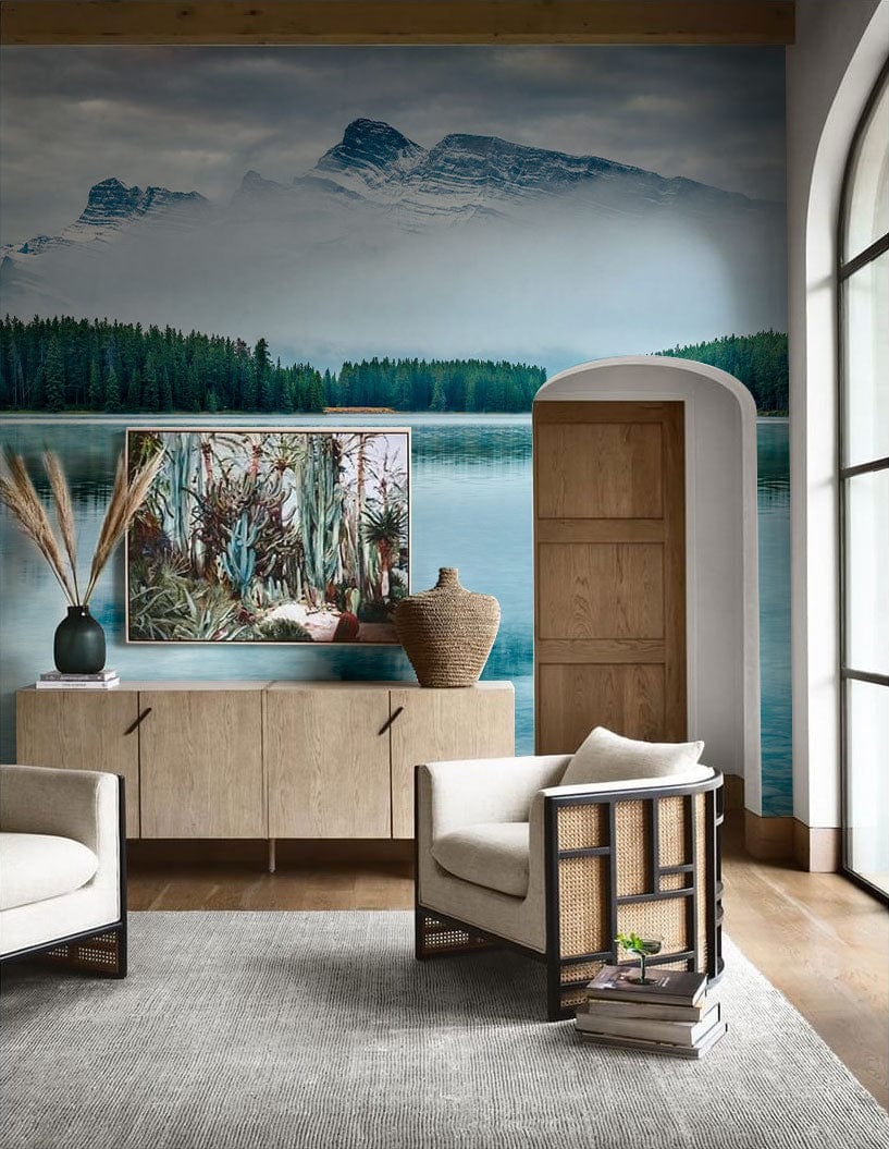 Serene Alpine Lake Mural Wallpaper with armchairs, wooden flooring, arched window, and a neutral sideboard.