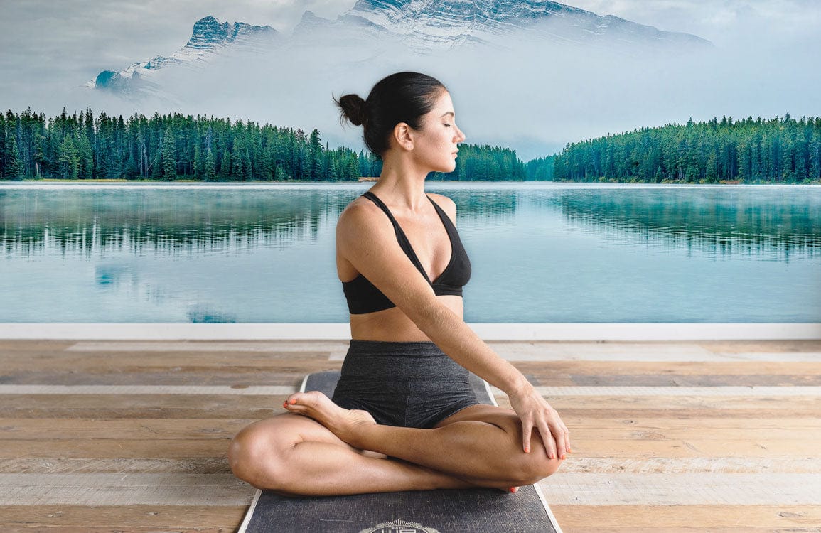 Yoga in living room with tranquil Serene Alpine Lake Mural Wallpaper, wooden flooring, and scenic lake.