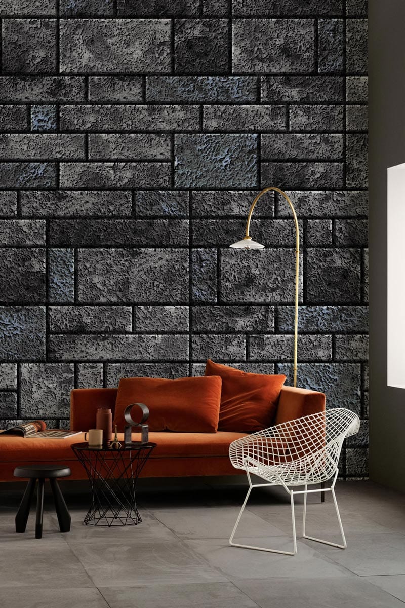 Elegant grey stone brick wallpaper, orange sofa, modern chair, lamp, and grey tile flooring.