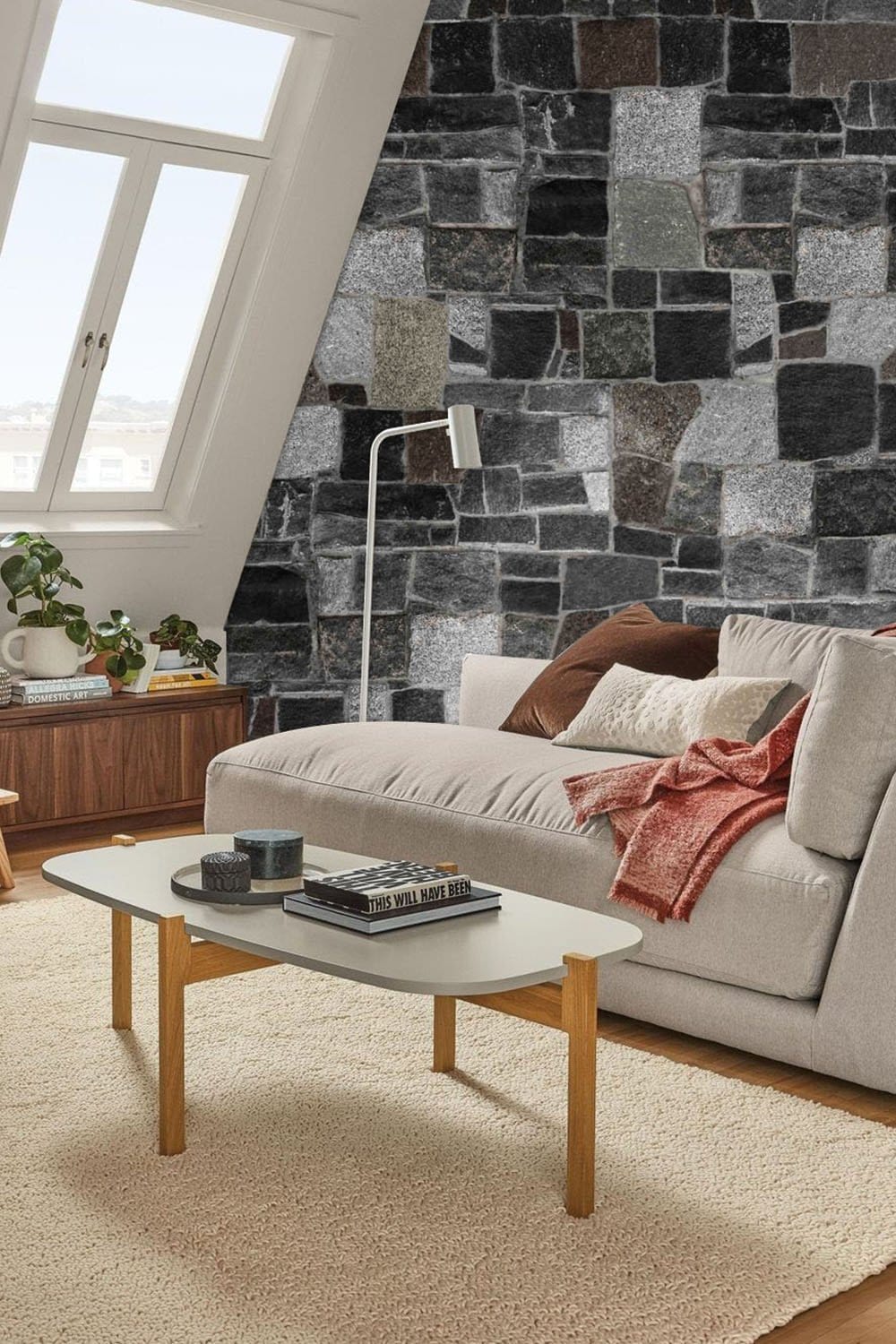 Rustic stone brick wallpaper in grey tones, modern grey sofa, light wooden coffee table, cosy living room.