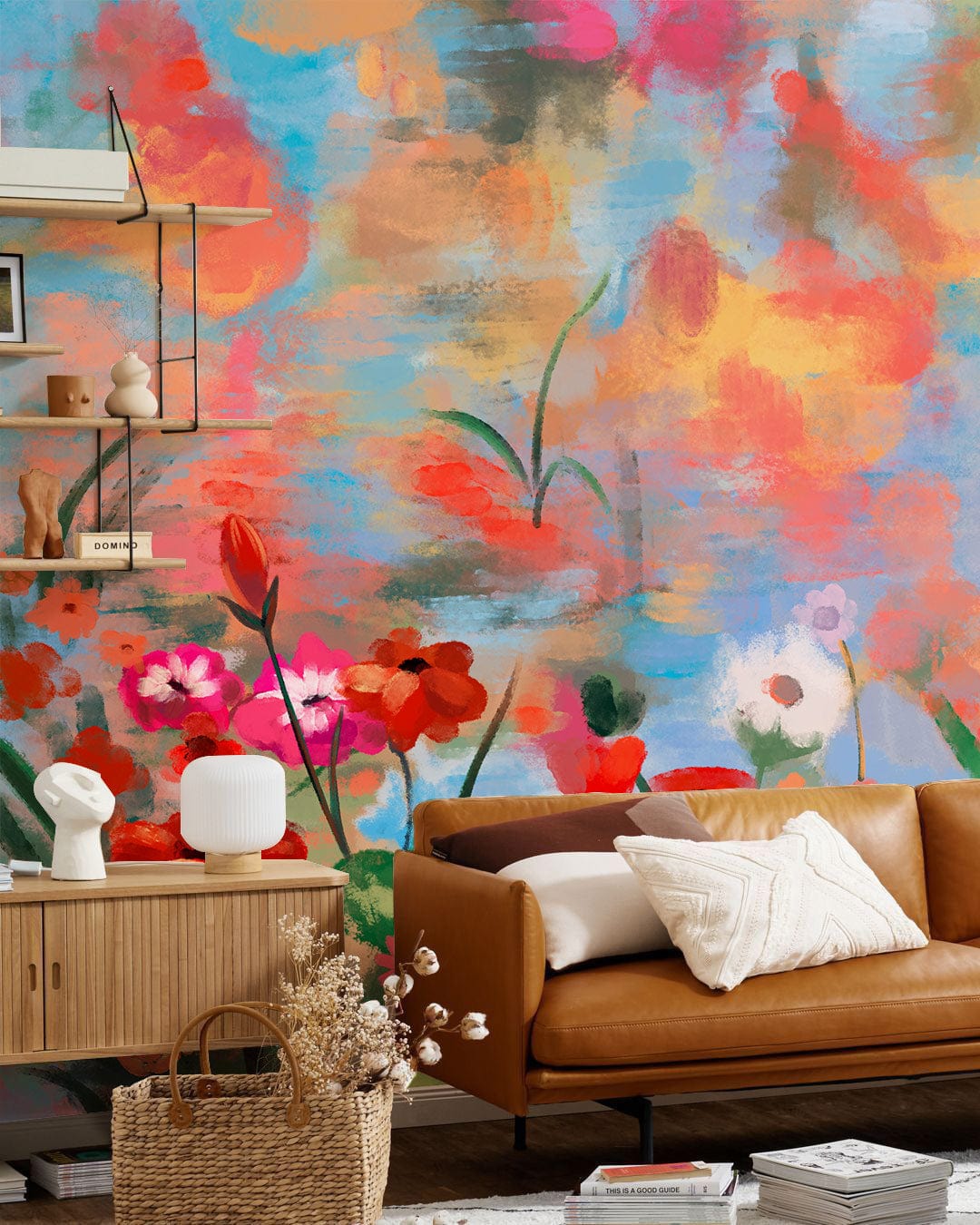 Vibrant watercolour mural wallpaper, multicolour; tan leather sofa, wooden cabinet, basket decor in living room.