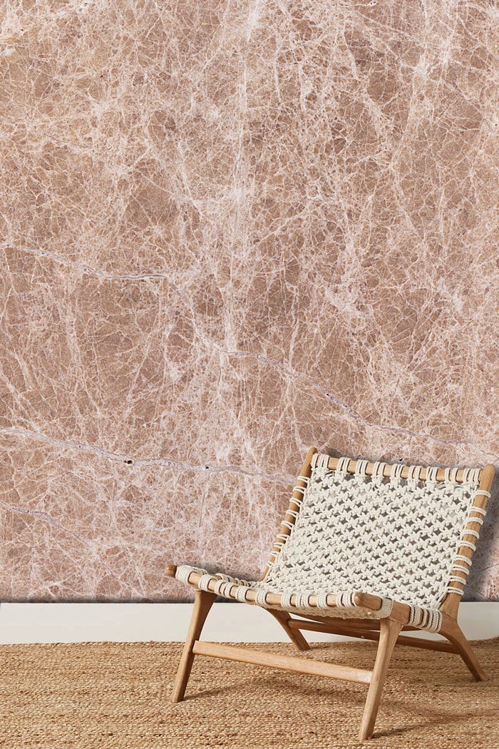 Elegant beige marble texture wallpaper with woven chair, natural rug, in a modern interior setting.