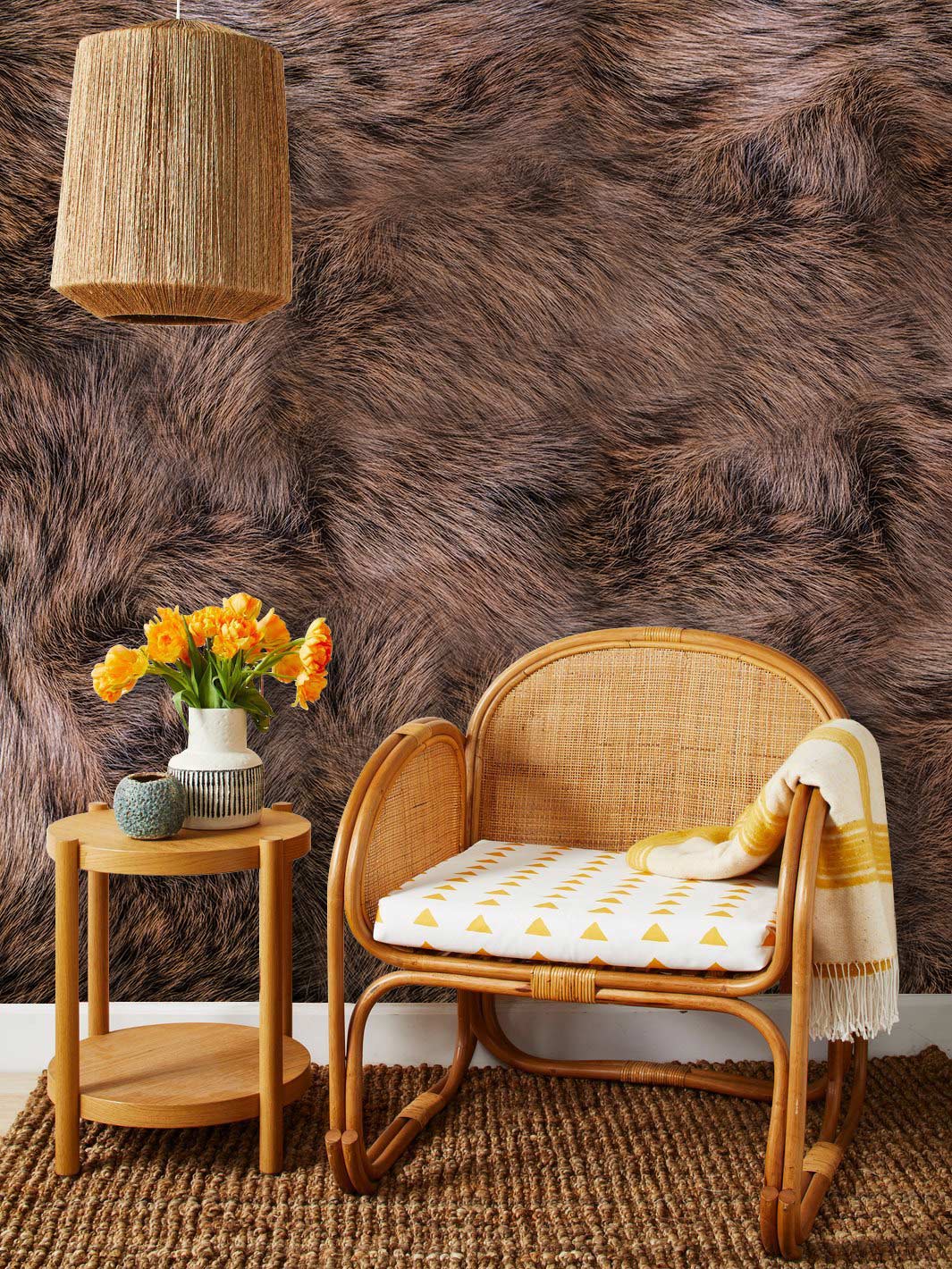 Brown faux fur wallpaper in cosy room, rattan chair, woven lampshade, natural fibre rug flooring.