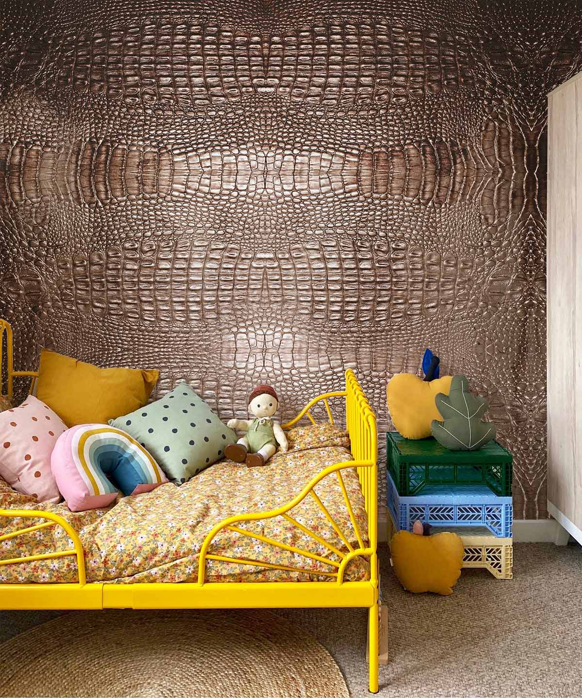Luxurious bronze crocodile pattern wallpaper, kids room, yellow metal bedframe, textured rug, colourful cushions.