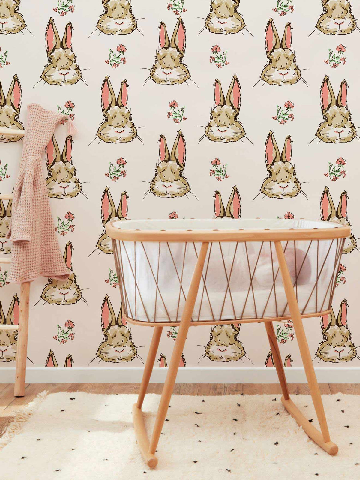 Charming Bunny wallpaper in pastel nursery, featuring wooden crib and soft rug on hardwood flooring.