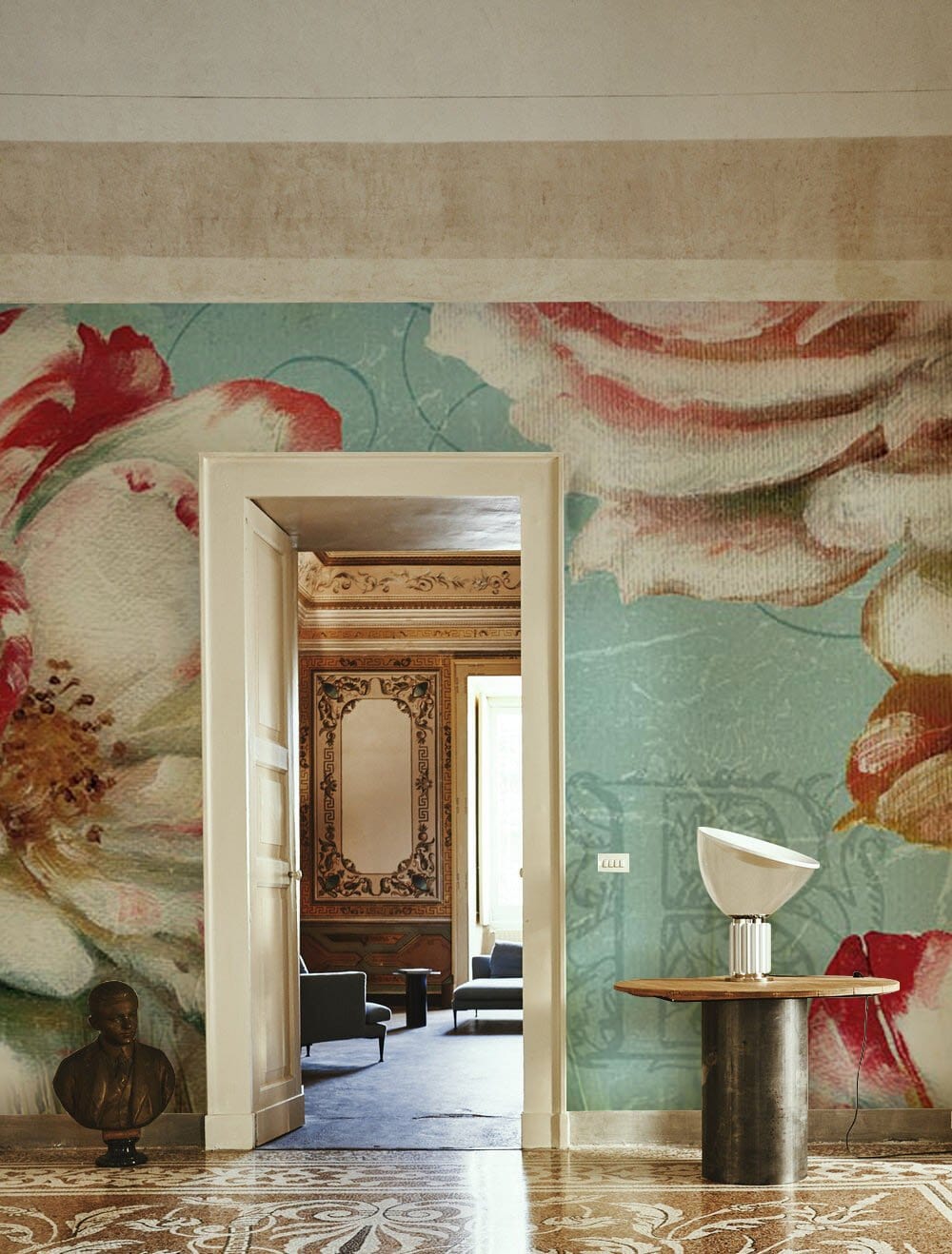 Vintage floral wallpaper in pastel green, ornamental flooring, accented by classic furniture and decor.