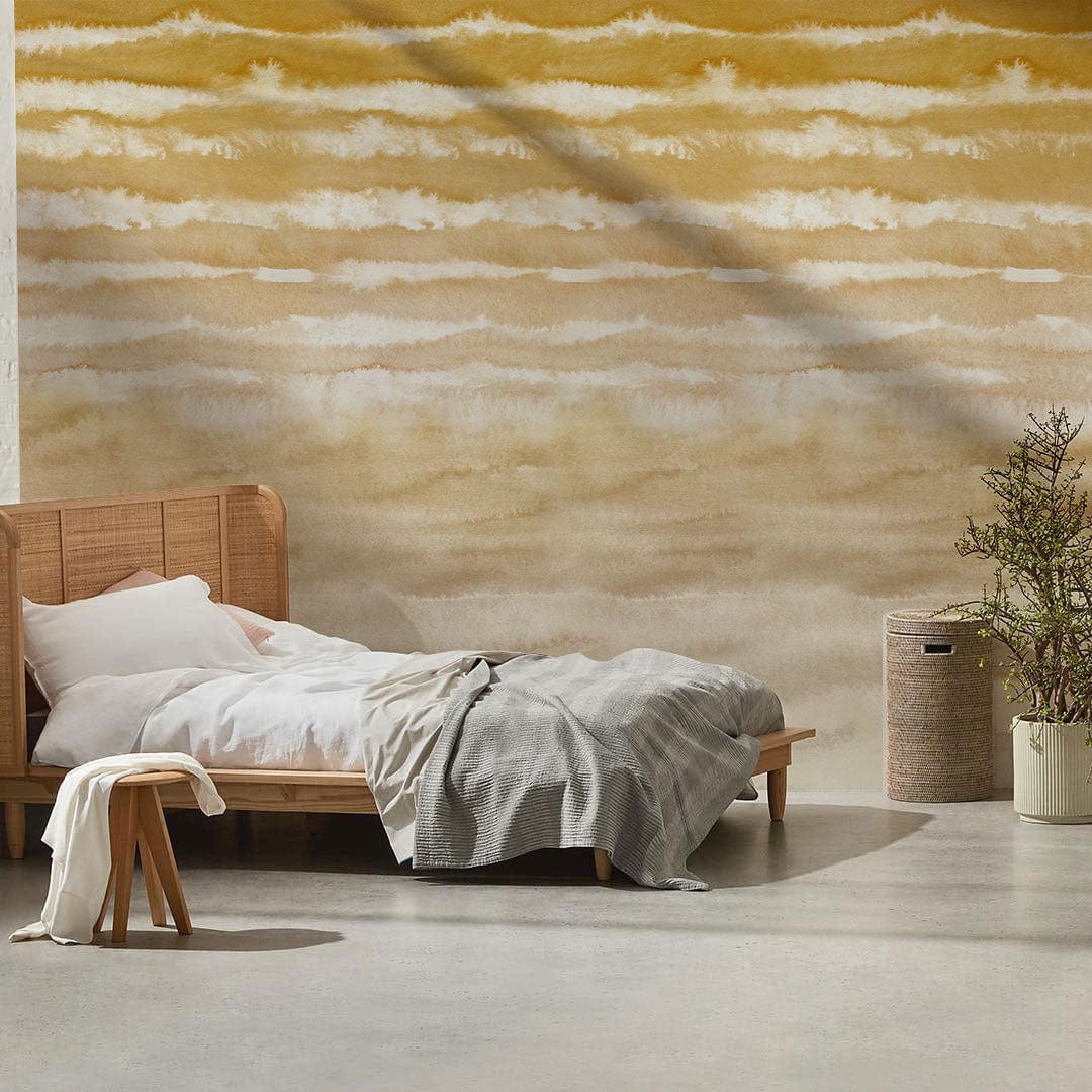 Elegant wallpaper with golden sand watercolour waves, wooden bed, grey blanket, minimalist bedroom decor.