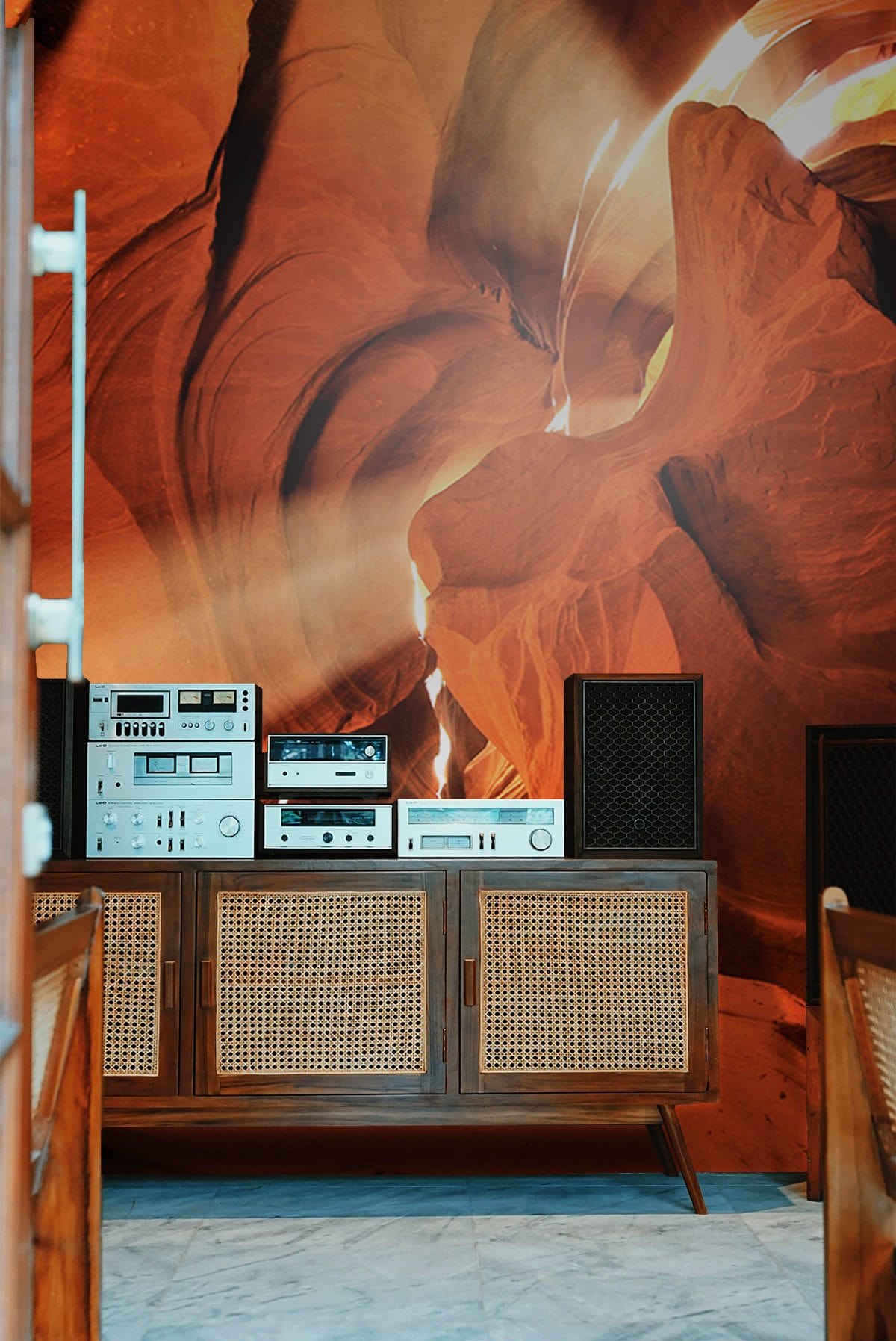 Sunlit Canyon Glow Mural Wallpaper with vintage stereo on mid-century cabinet, marble flooring in living room.