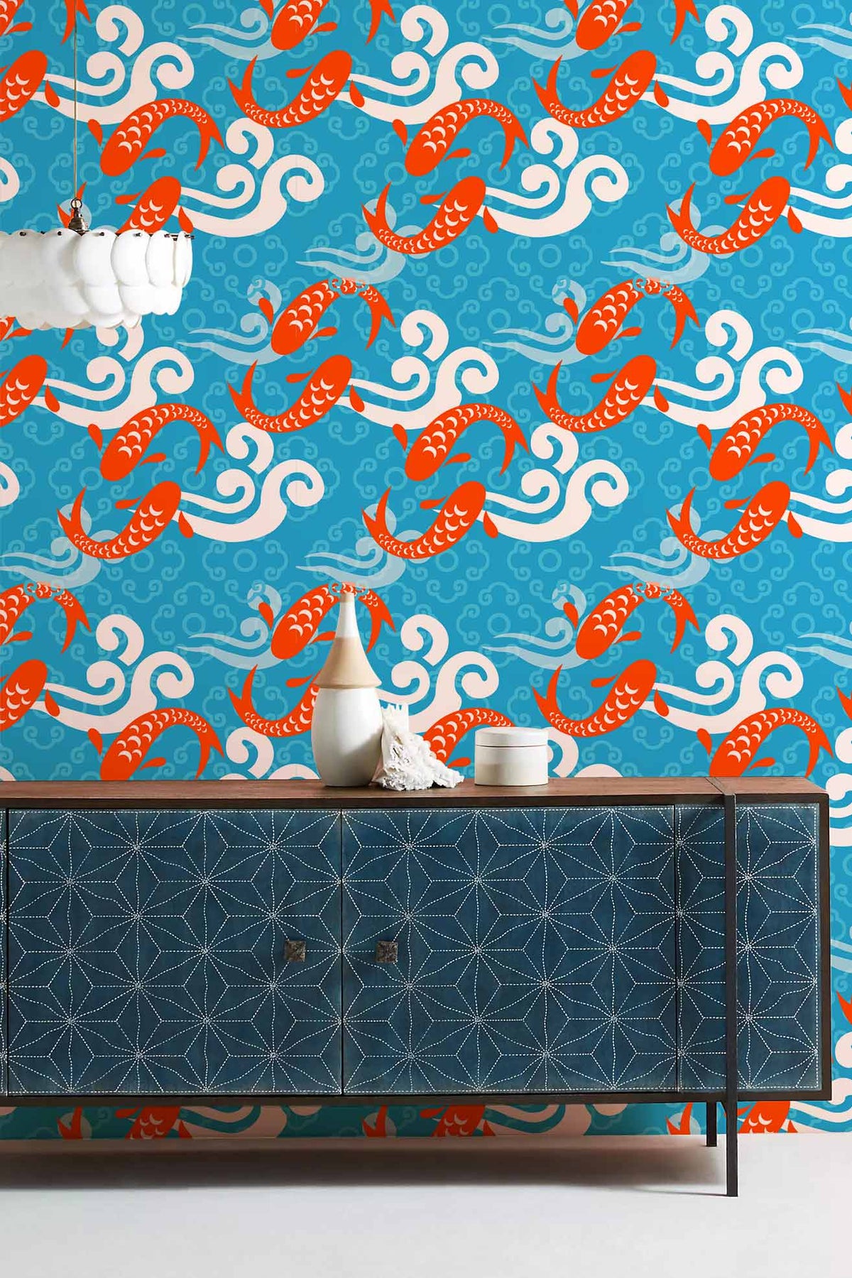 Vibrant blue and orange koi fish wallpaper with geometric patterned sideboard in living room setting.