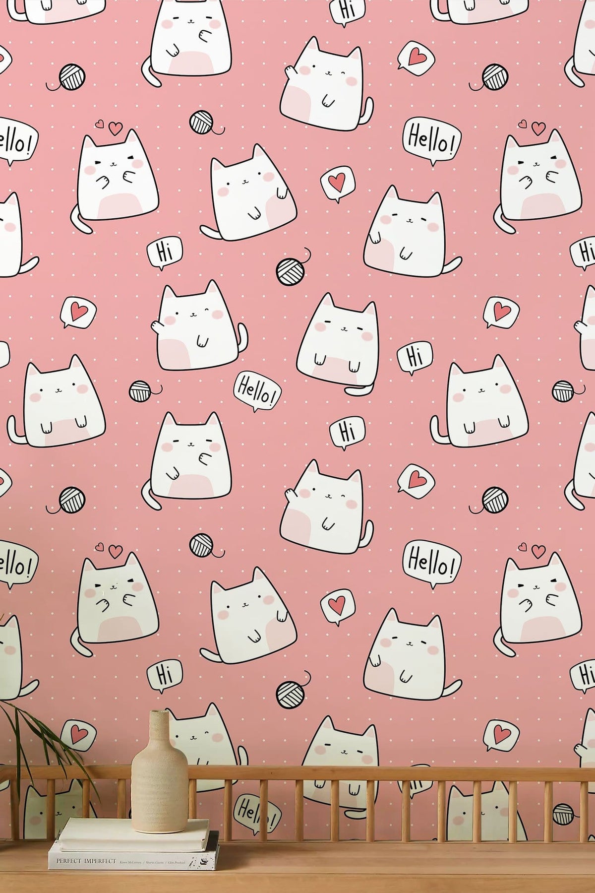 Cute cat pattern wallpaper on pink wall in children's room with playful decor elements.