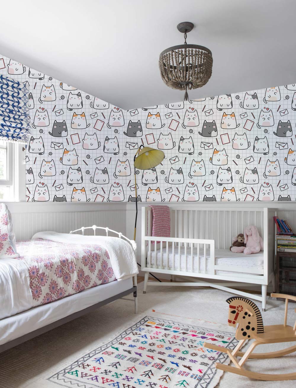 Nursery with cute cartoon cat wallpaper, white crib, and whimsical grey design accents, light beige carpet.