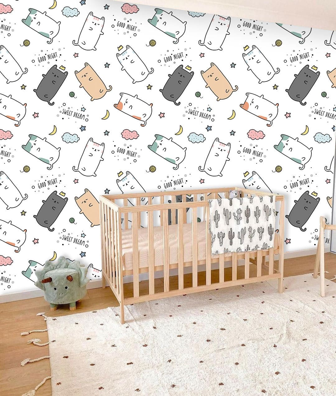 Playful pastel cat pattern wallpaper, kids' room decor; wooden crib, carpet, white walls, nursery setting.