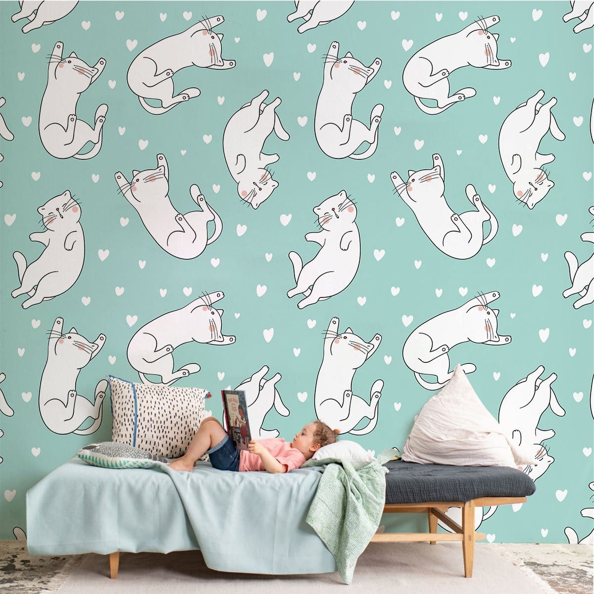 Playful white cats wallpaper on pastel mint background, light blue sofa, wooden flooring, cosy room.