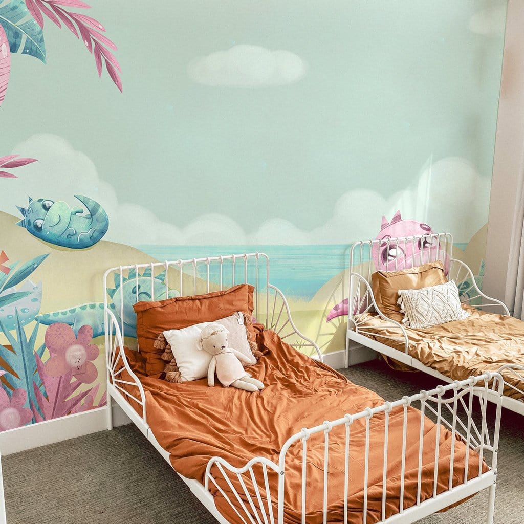 Scenic nursery mural with pastel dinosaurs, white beds, orange bedding, beige carpet, wall mural.