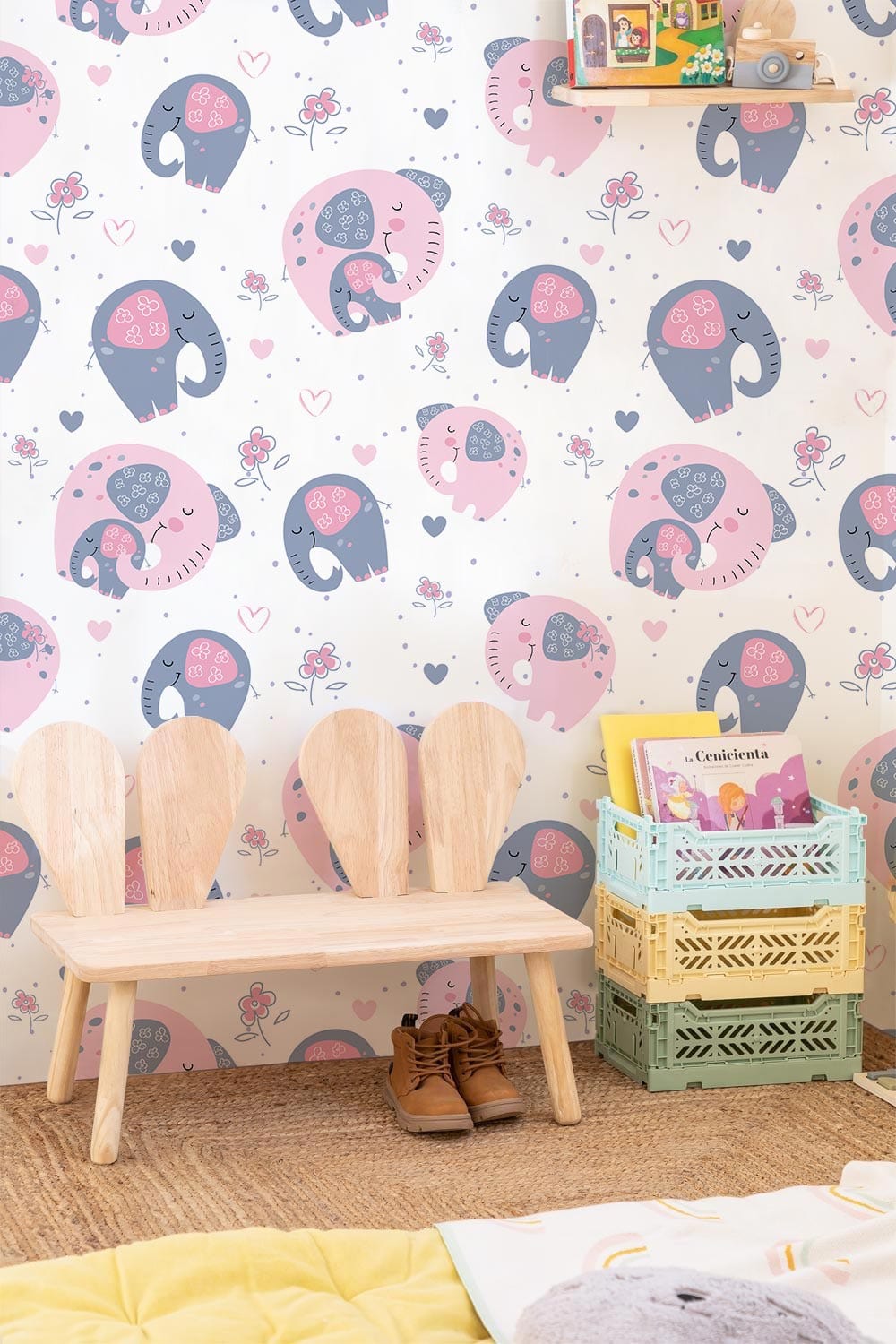 Adorable pink and grey elephant nursery wallpaper with wooden bench, wicker flooring, colourful storage boxes.