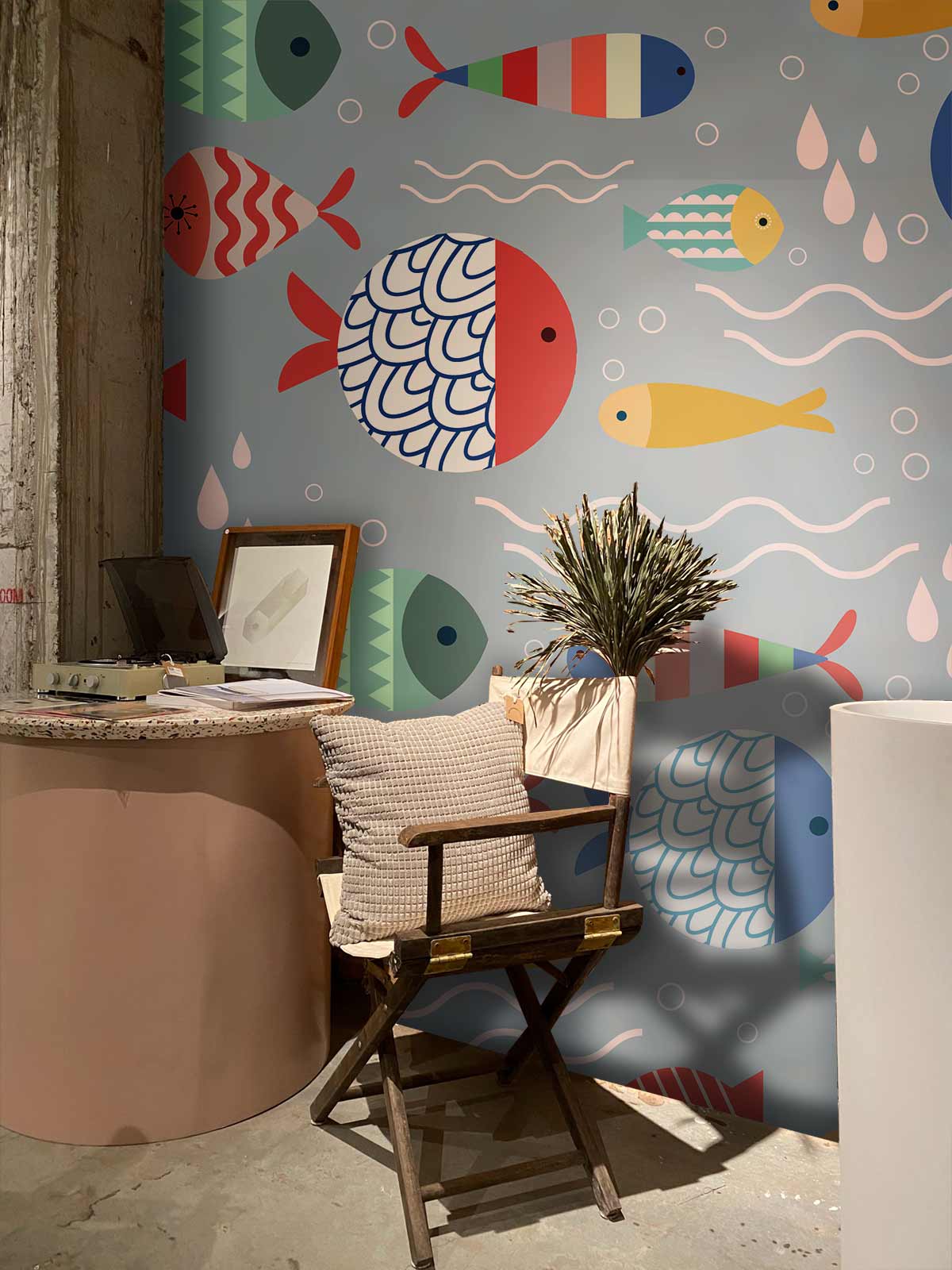 Playful underwater fish pattern wallpaper, vibrant colours, rustic wooden chair, modern round table, concrete floor.