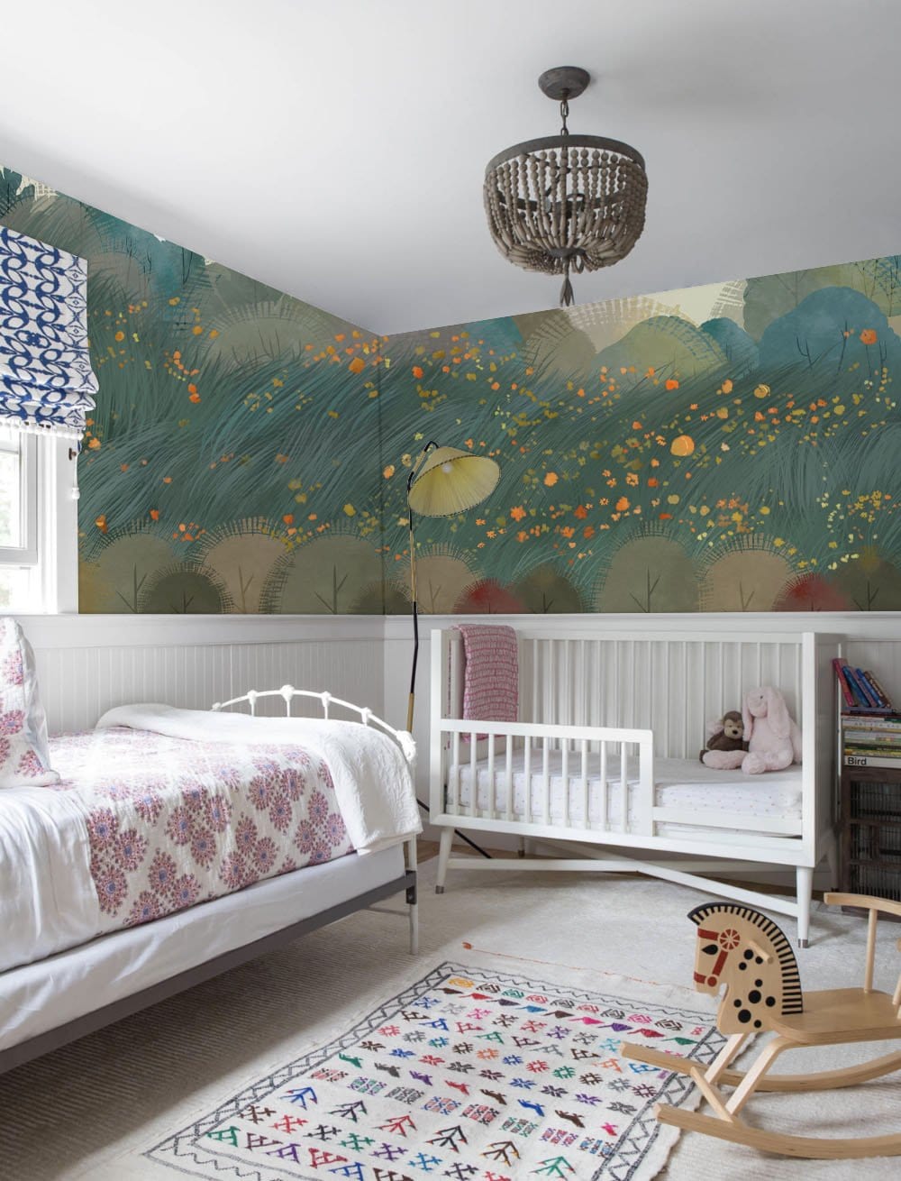 Enchanted Forest mural in teal tones in nursery with white cot, patterned rug, and pendant light.