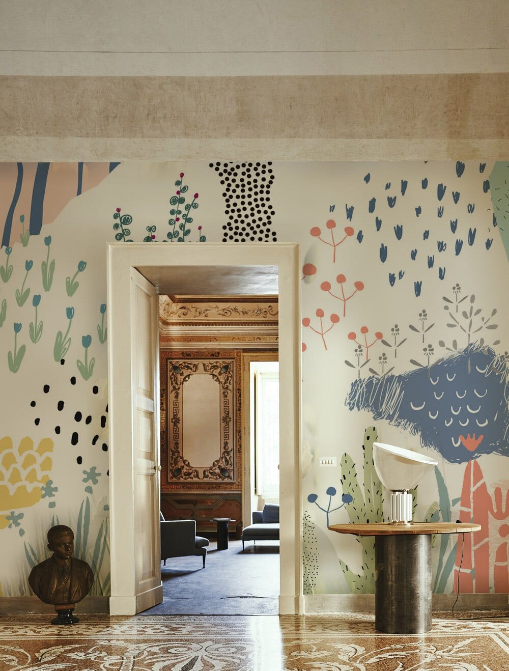Colourful abstract botanical design mural in modern interior with ornate floor, doorway view, rustic table.