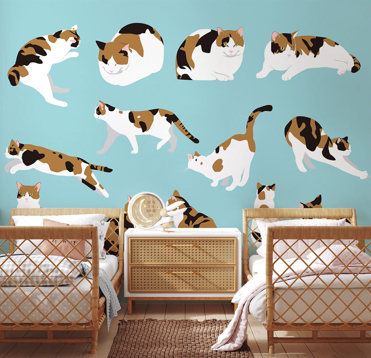 Charming calico cats wallpaper, blue wall; bedroom with rattan furniture, beige cushion, wooden flooring.
