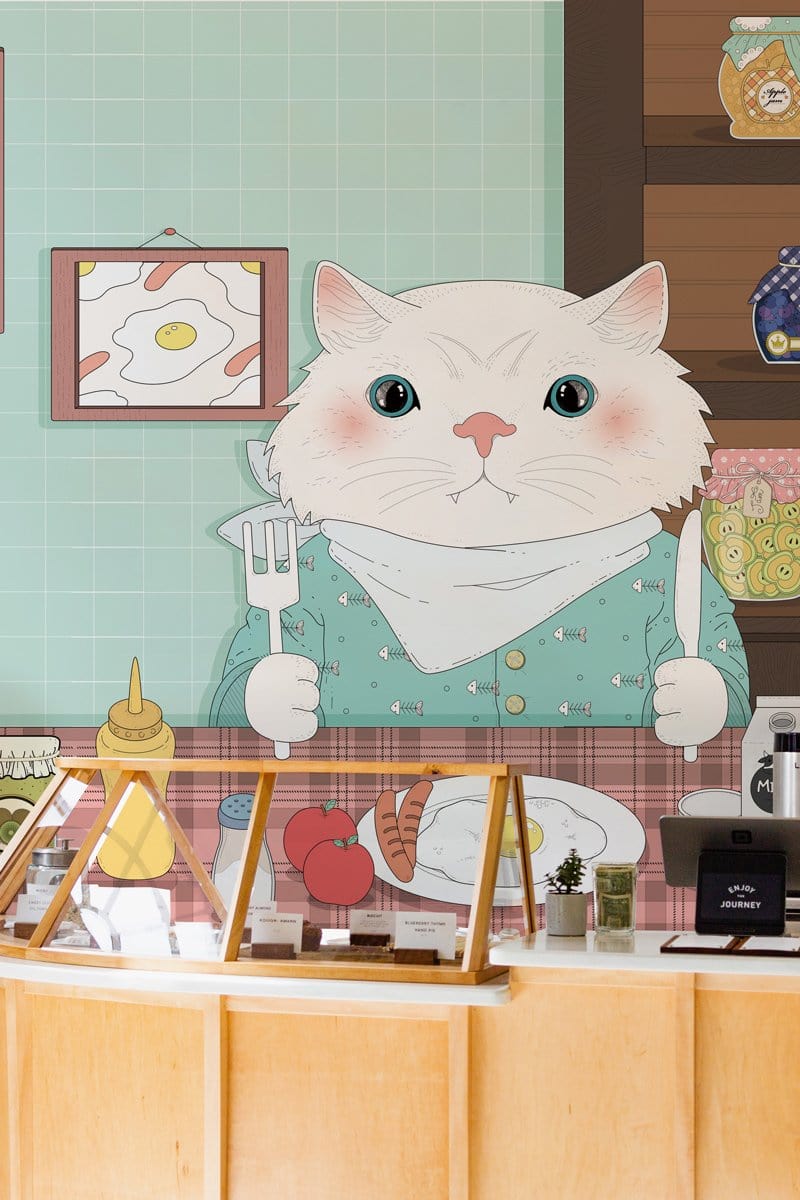 Charming Pastel Cat Kitchen Mural Wallpaper with teal tiles and wooden counter in cosy café setting.