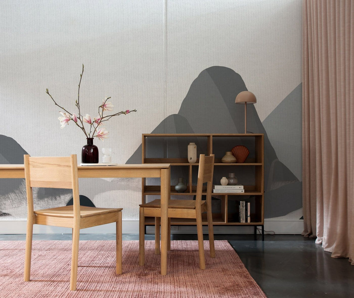 Tranquil grey mountain mural wallpaper in minimalist room with wooden furniture and pink textured rug.