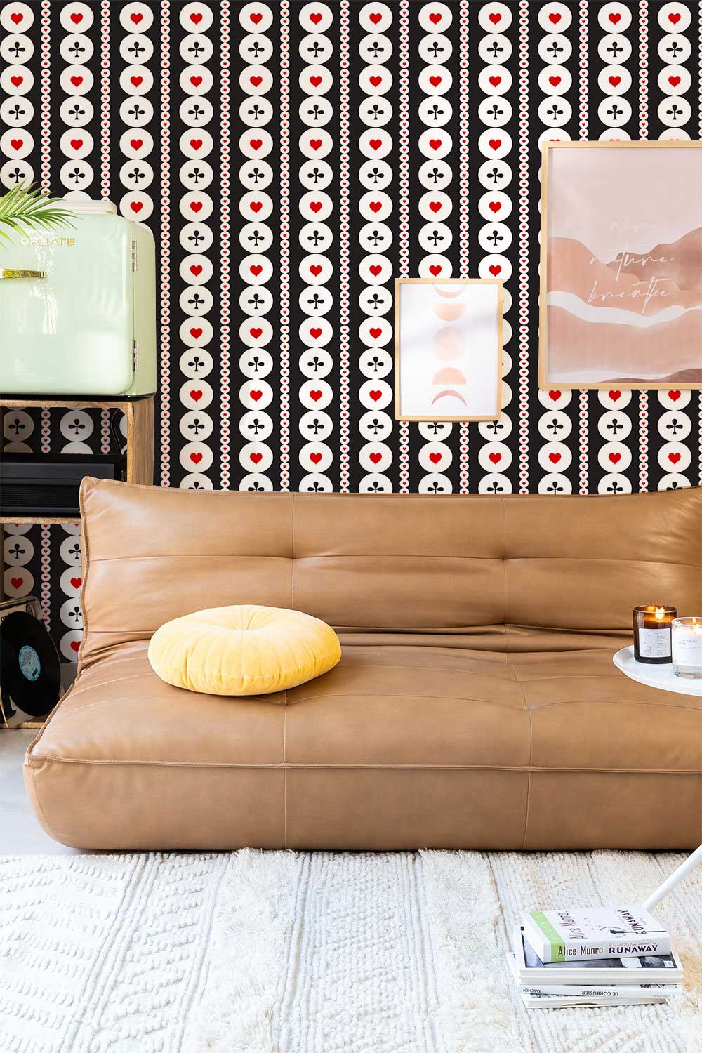 Retro geometric wallpaper with red accents, brown sofa, light rug, and artwork in modern living room.