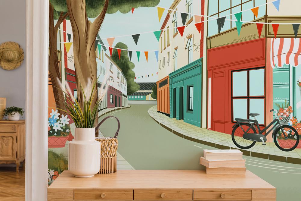 Charming Vintage Village Bicycle Scene Mural Wallpaper with pastel tones, featuring sideboard and wood flooring.