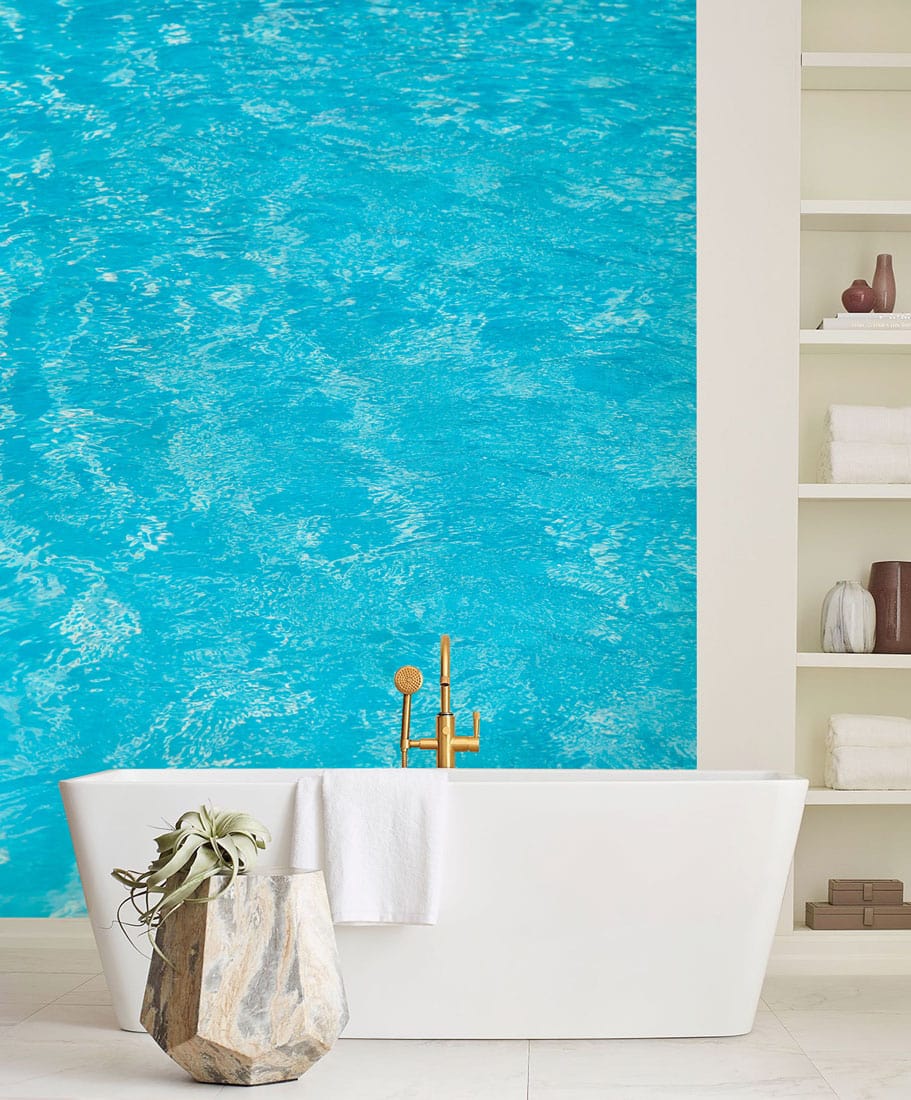 Turquoise water texture mural wallpaper, white freestanding bathtub, elegant bathroom decor, and minimalist shelving.
