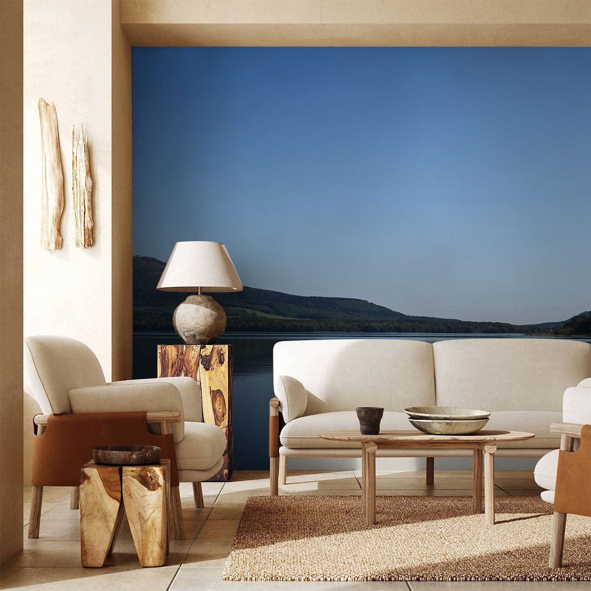 Tranquil Blue Lake Mural Wallpaper, beige sofa, wooden lamp, mountain view; serene minimalist living room.