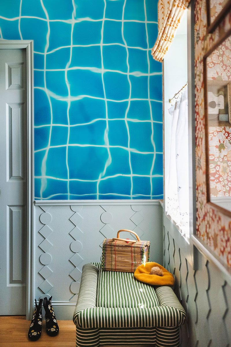 Aqua blue grid wallpaper, hallway; green striped bench, parquet flooring, textured wall panelling.