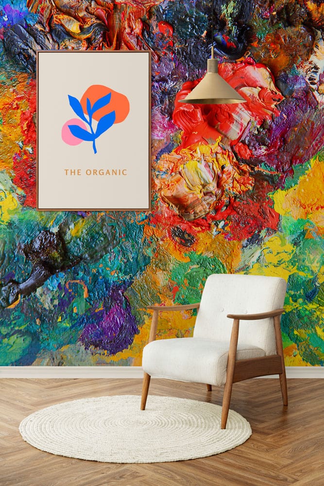 Vibrant abstract mural wallpaper, white armchair, wooden floor, pendant light; colourful creative interior setting.
