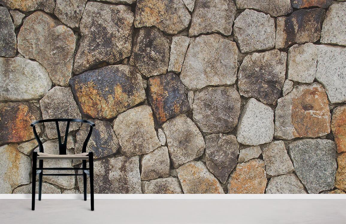 Rustic stone wall effect wallpaper mural in natural tones, with black chair on light flooring.