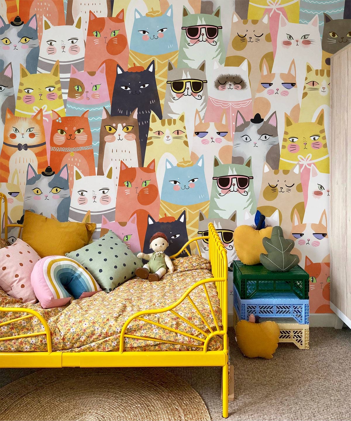 Colourful whimsical cat wallpaper, yellow metal bed, playful children's room decor with cosy cushions.