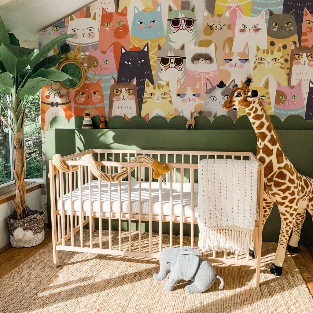 Colourful Cats Wallpaper in Whimsical Design; nursery with natural crib, giraffe decor, basket.