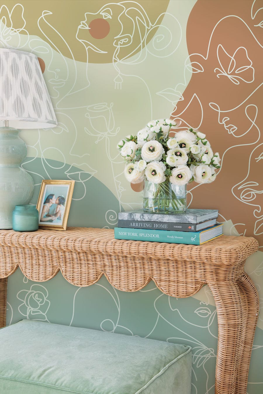 Abstract pastel wallpaper in living room with wicker table, green lamp, and mint cushion.
