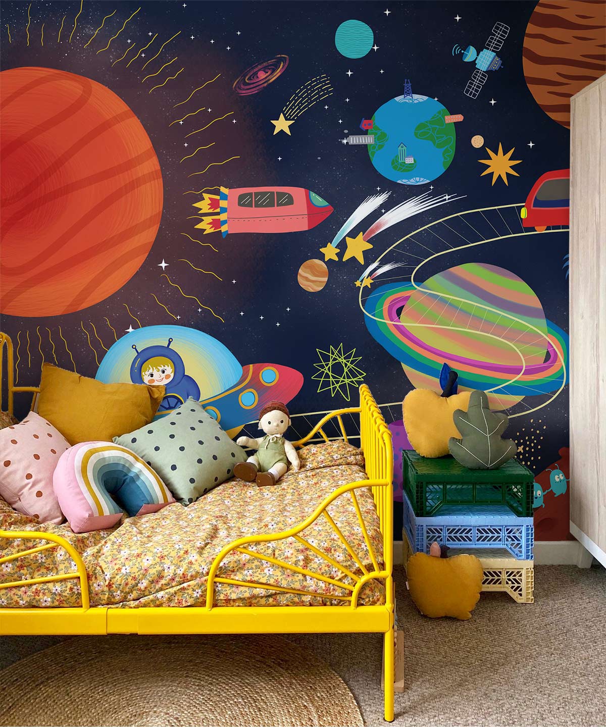 Yellow bed with toys, space-themed mural wallpaper, colourful decor, rug in kid's room. Cosmic fun.