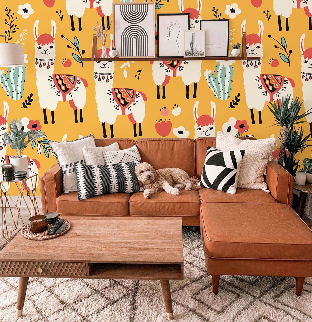 Playful Llama Safari Wallpaper in vibrant orange, featuring a boho chic nursery design with brown sofa.