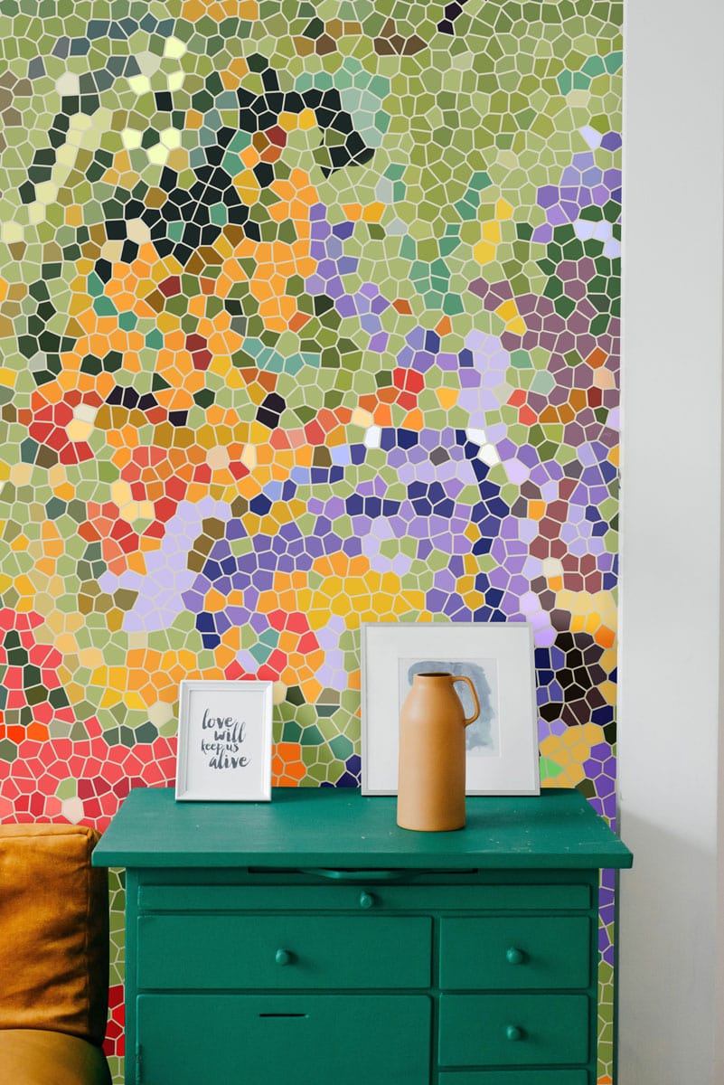 Vibrant mosaic mural wallpaper, green chest of drawers, colourful geometric patterns, cosy living room setting.